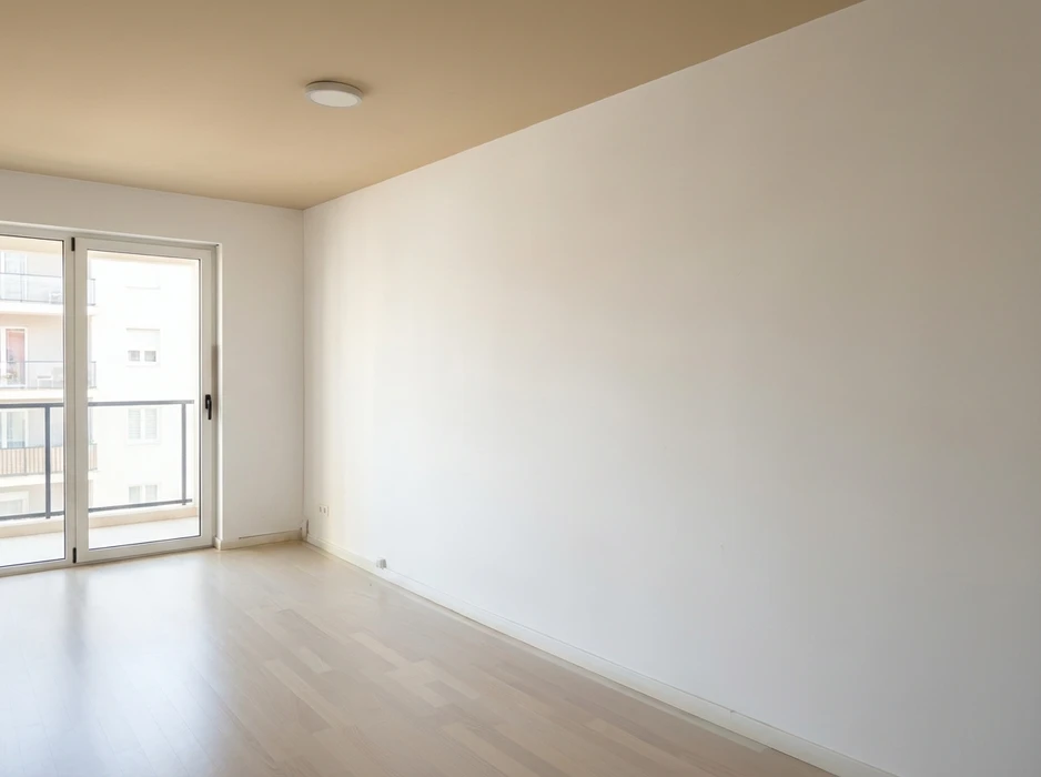 Pièce vide et lumineuse avec parquet stratifié clair, murs blancs et plafond légèrement beige