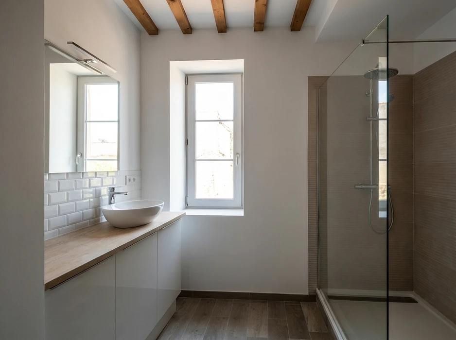 Salle de bain moderne et lumineuse, deux fenêtres à battants blancs, vasque à poser ovale sur plan de travail bois, mitigeur chromé, carrelage métro blanc, grand miroir éclairé
