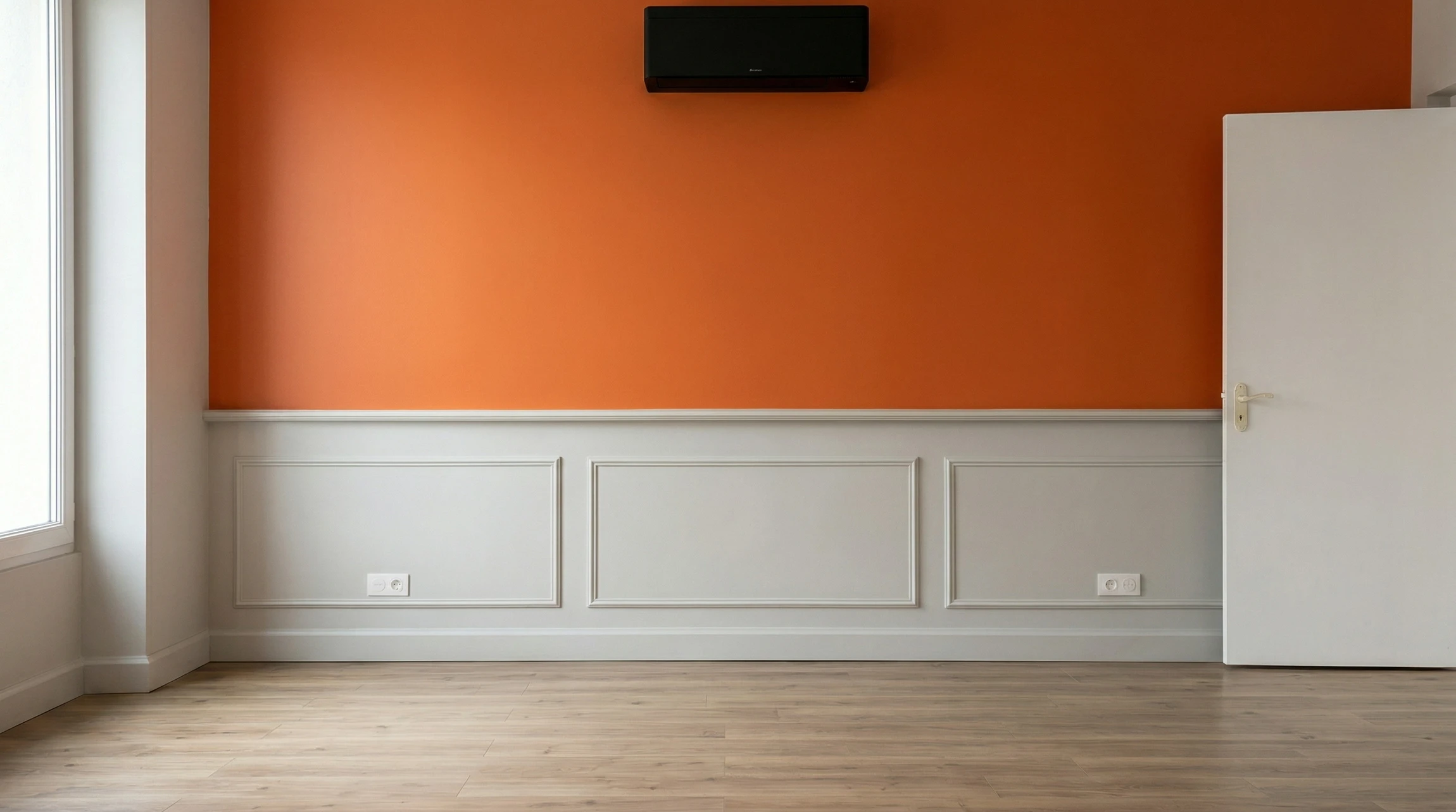 Une main tient un pinceau plat à manche vert chargé de peinture orange au-dessus d'un pot de peinture blanc ouvert
